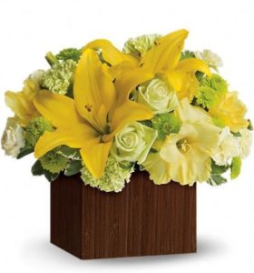 Striking yellow lilies, green roses and carnations pop in this wonderfully designed cube.