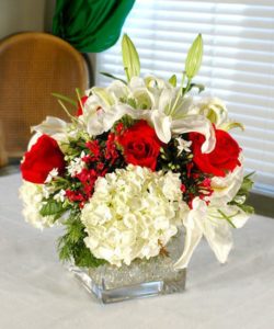 This beautiful cube vase is filled with hydrangea, lilies, red roses and more. It's simply perfect for any setting.